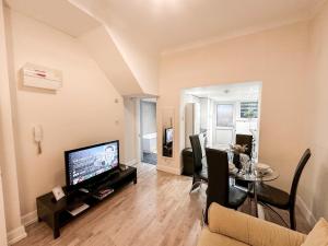 a living room with a television and a table at Charming apartment with a small garden in Finsbury Park in London