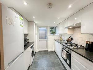 a kitchen with white cabinets and a stove top oven at Charming apartment with a small garden in Finsbury Park in London