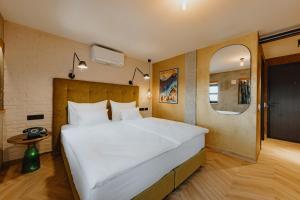 uma grande cama branca num quarto com um espelho em ONE66 Hotel em Liubliana
