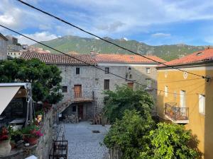an alleyway in a town with buildings and mountains at Appartement familial au cœur du village d’Olmeto in Olmeto