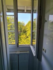 a window in a bathroom with a view of trees at Maison Briand - Chambre Confortable Melun Centre - Wifi, Netflix, Smart TV, Lit à mousse mémoire de forme in Melun