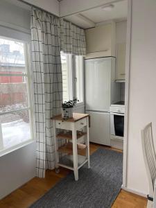 eine Küche mit einem Kühlschrank, einem Tisch und einem Fenster in der Unterkunft Yksiö Pispalassa in Tampere