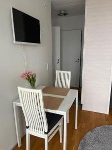 einen Esstisch mit 2 weißen Stühlen und einem TV in der Unterkunft Yksiö Pispalassa in Tampere