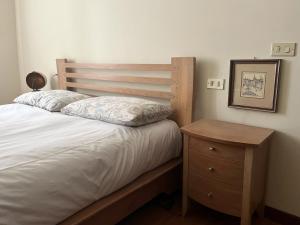 uma cama com uma cabeceira em madeira e uma mesa de cabeceira em madeira em Clodì em Milão
