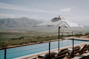 a swimming pool with a white umbrella and chairs at Khanyisa Mountain Lodge in Robertson