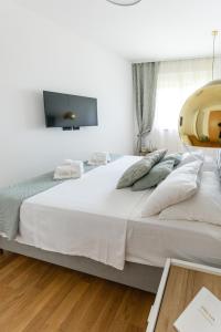 a bedroom with a large white bed with a tv on the wall at Villa Lux ZadarVillas in Zemuniki