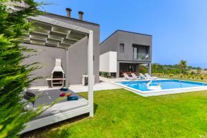 a house with a swimming pool in a yard at Villa Lux ZadarVillas in Zemuniki