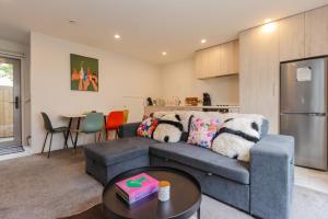 a living room with a gray couch and a kitchen at stylish and comfort in CBD in Christchurch