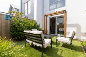 a patio with two chairs and a table on the grass at stylish and comfort in CBD in Christchurch