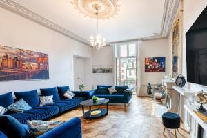 un salon avec des canapés bleus et un lustre dans l'établissement Appartement immeuble le bringer 180m2, à Marvejols