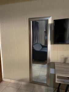een spiegel in een kamer met een bank en een televisie bij Tshiamo Estate in Kuruman