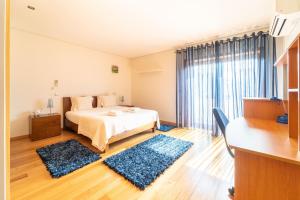 a bedroom with a bed and two blue rugs at Casa de Palmeira by House and People in Burgueiros