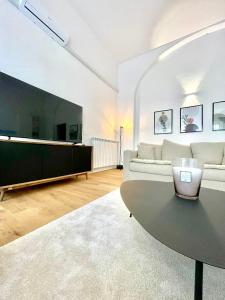 ein Wohnzimmer mit einem weißen Sofa und einem großen TV in der Unterkunft I Marmi New Royal Design Apartment in Livorno