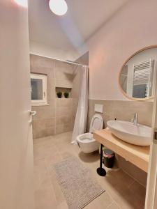 ein Badezimmer mit einem Waschbecken, einem WC und einem Spiegel in der Unterkunft I Marmi New Royal Design Apartment in Livorno
