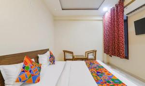 a bedroom with a white bed with colorful pillows at FabHotel The Gahmar Inn in Lucknow