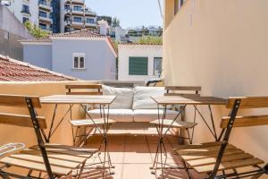 eine Terrasse mit Stühlen und einem Sofa auf dem Balkon in der Unterkunft Cozy Coastal Getaway 3BR Apartment in Estoril in Estoril