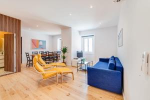 ein Wohnzimmer mit einem blauen Sofa und gelben Stühlen in der Unterkunft Cozy Coastal Getaway 3BR Apartment in Estoril in Estoril