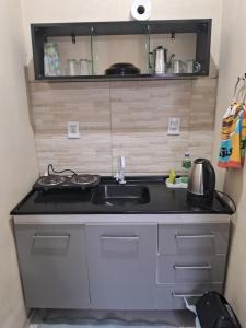 uma pequena cozinha com um lavatório e um fogão em Pousada Luz Beira mar em Tramandaí