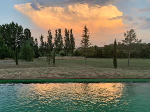 a pool of water with trees and a sunset at Brin de Cocagne in Fénols