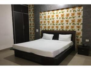 una camera da letto con un grande letto bianco con una parete floreale di Hotel Alpine, Kurukshetra a Kurukshetra