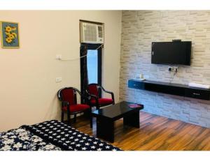 una camera con un letto e due sedie e una televisione di Hotel Alpine, Kurukshetra a Kurukshetra
