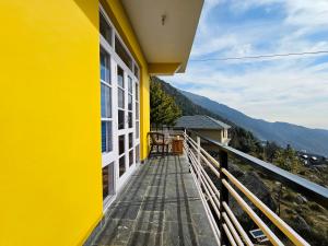 ein gelbes Haus mit einem Balkon mit Aussicht in der Unterkunft Young Monk Hostel & Cafe Dharamkot in McLeod Ganj