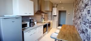 une cuisine avec des armoires blanches et une table en bois dans l'établissement appartement 2 chambres, à Baccarat