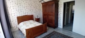 une chambre avec un lit et une armoire en bois dans l'établissement appartement 2 chambres, à Baccarat