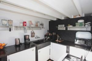 uma cozinha com armários brancos e um balcão preto em De Peirdestal em Pittem