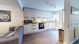 a kitchen with white cabinets and a couch in a room at Oxford Bolthole in Oxford