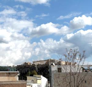um edifício numa colina com nuvens no céu em AIONION RESIDENCES by K&K em Atenas