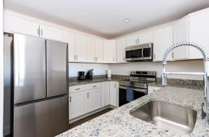 a kitchen with white cabinets and a stainless steel refrigerator at 1BR Luxury Apartment Peabody - Unit #606 in Peabody