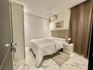 a white bedroom with a bed and a window at Garden Suites in Nouakchott