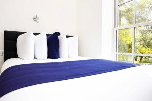 een bed met blauwe en witte kussens en een raam bij Stylish Studio in Historic Boston - Unit #205 in Boston