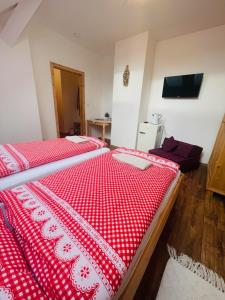 a bedroom with two beds with a red and white comforter at Penzion U Hánů in Meclov