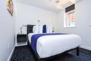 ボストンにあるModern Studio in Historic Boston - Garden Unit #1の白いベッドルーム(青いシーツを使用した大型ベッド1台付)