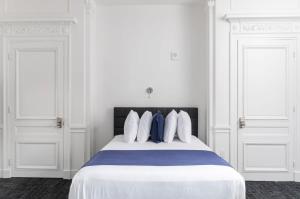 a white bedroom with a large bed with blue pillows at Stylish Studio in Historic Boston - Unit #204 in Boston
