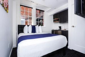 1 dormitorio con 1 cama blanca grande con almohadas azules en Modern Studio in Historic Boston - Garden Unit #4 en Boston