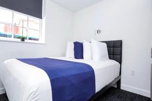 uma cama com lençóis azuis e brancos e uma janela em Modern Studio in Historic Boston - Garden Unit #2 em Boston mais 6 fotografias