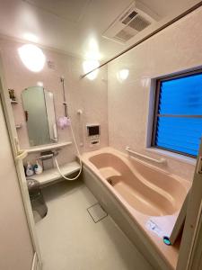 bagno con vasca, lavandino e specchio di 孔雀民宿 ad Osaka