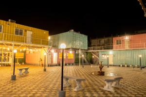 MundraClick Hotel Mundra的夜晚的庭院，有长椅和建筑物