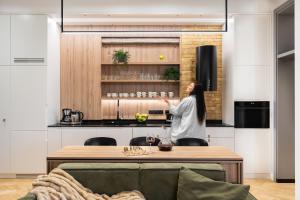 a woman standing in a kitchen with a table at Helska 11 - Apartamenty blisko plaży i Monte Cassino - topowy adres by Lion Apartments in Sopot