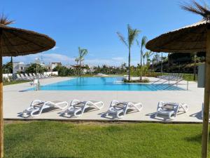 una piscina con tumbonas y sombrillas en AL-321 Penthouse 3 bedrooms Alcazaba Lagoon, en Estepona