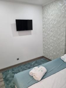 a bedroom with two towels on a bed with a flat screen tv at Mikaela Guest House in Odivelas