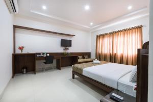 Dormitorio con cama, escritorio y TV en Sanctum Suites BEL Road Bangalore, en Bangalore