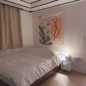 a bedroom with a bed with a painting on the wall at Yudama Gangneung in Gangneung