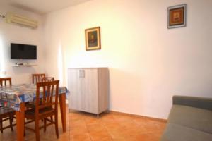 un salon avec une table, des chaises et une télévision dans l'établissement Primavera, à Marina di Campo