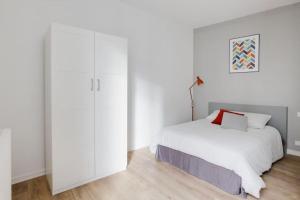 een witte slaapkamer met een bed en een witte kast bij Aux Clefs des Sacres - Le Chabaud 5 in Reims