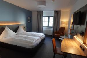 ein Hotelzimmer mit einem Bett und einem Stuhl in der Unterkunft Hotel & Weinhaus Zum Schwarzen Bären in Koblenz
