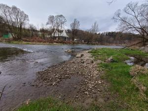 a river with some grass and a house in the background at Miętówka in Żywiec